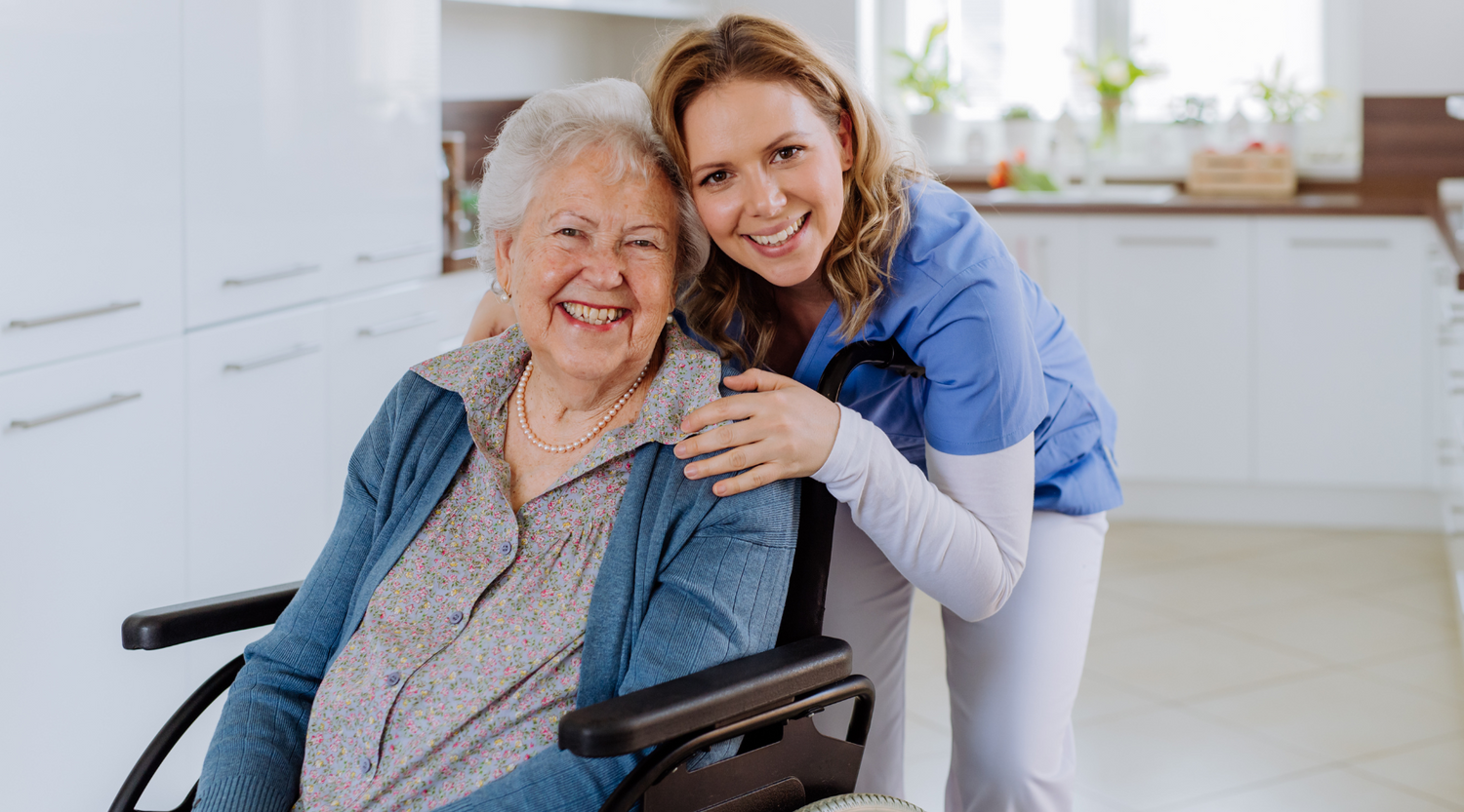 Smiling caregiver with senior woman in a wheelchair at home, representing trust and support in home medical care